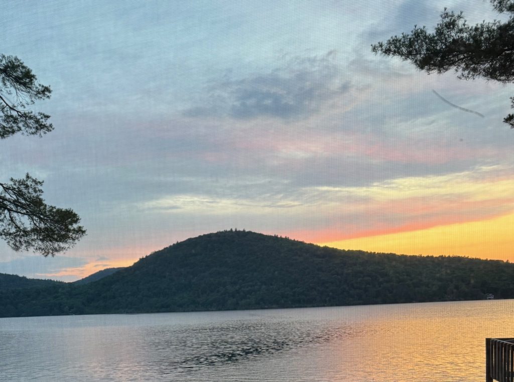 a sunset on the lake with mountains in the distance